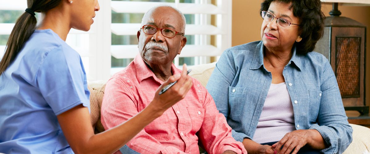 Nurse Making Notes During Home Visit With Senior Couple